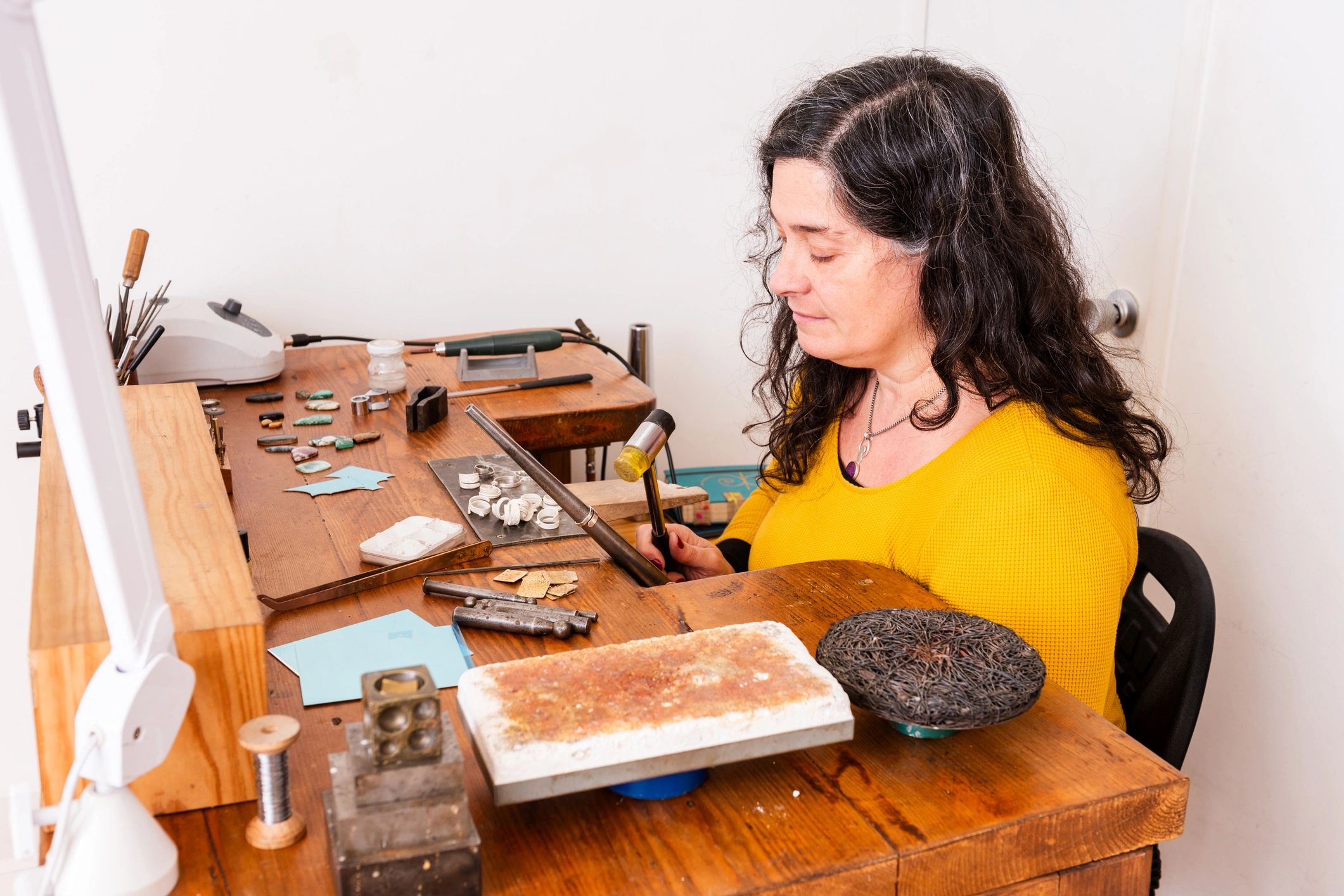 Jewelry maker shaping metal by hand in a workshop
